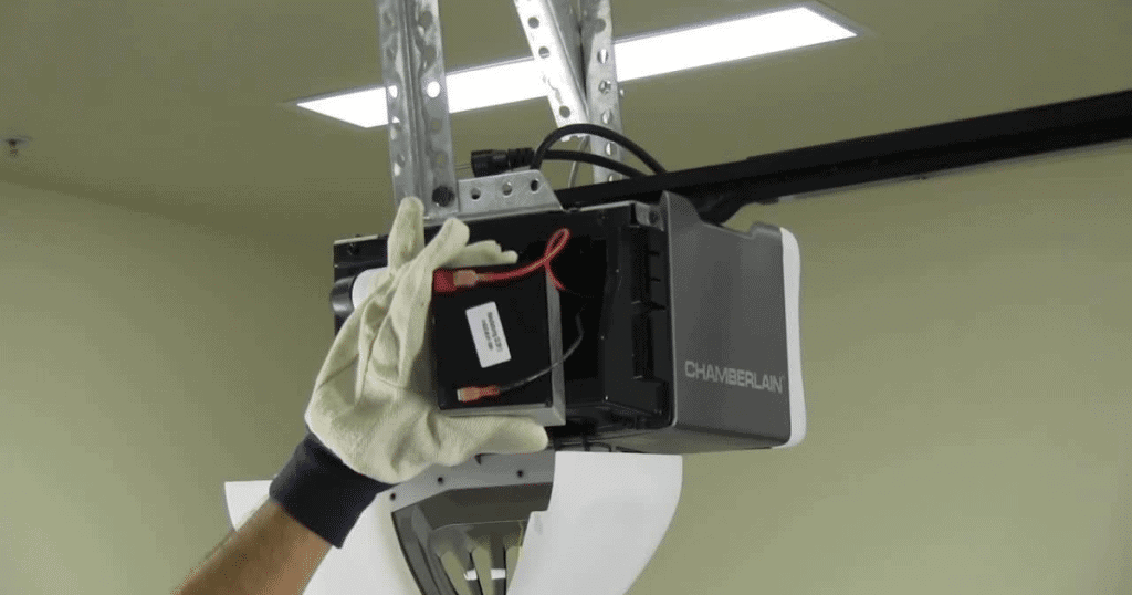 Gloved hand installs opener backup battery.