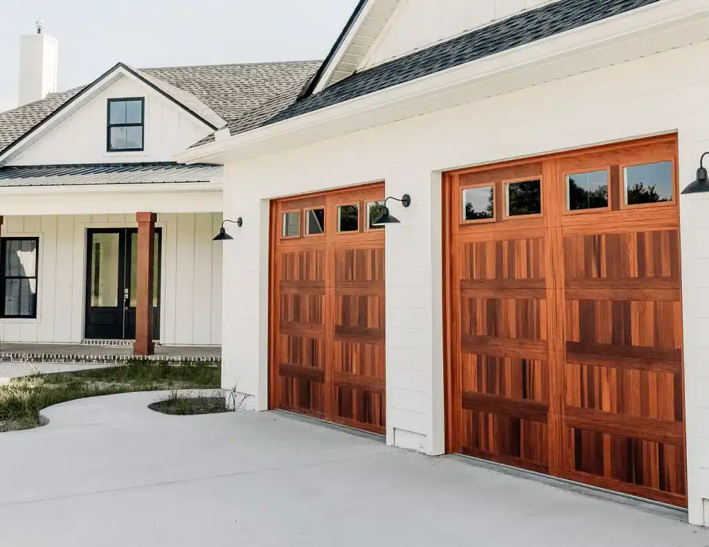 Contemporary wooden garage doors with windows, part of secure residential gate and fence system.